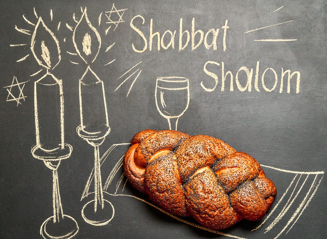 תמונה בה כיתוב בגיר המילים Shabbat Shalom לצד נרות שבת וחלה, כתמונת קאבר לפוסט אתר שומר שבת